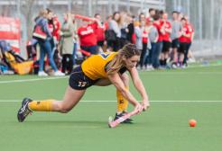 Group of students watching a hockey player about to hit a ball 