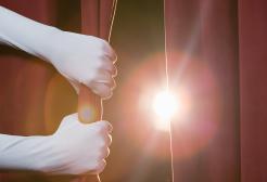 Hands drawing back a curtain