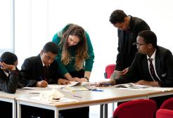 Children and staff member collaborating around a table in a school setting