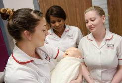 Three student nurses, one holding a doll baby