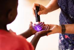 A special light torch shining on a child's hand