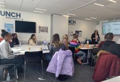 An image showing Launch users sat at desks in a classroom, paying attention to a speaker in front of a Smart board.