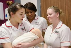 Midwifery students holding a dummy baby 