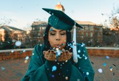 Graduate blowing confetti into the camera