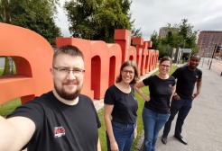 SalfordFASD team stood next to the Ambition sign on Peel Park campus, University of Salford
