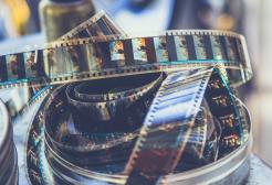 Vintage motion picture film and loose celluloid film strips inside a metal container