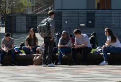 A group of students relax in the sunshine outside the Library