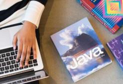 A person uses a laptop with books beside them