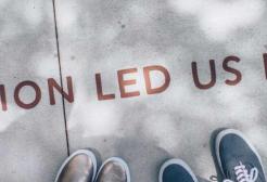 People look at a notice on the floor which says 'Passion led us here'