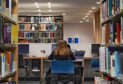 A student working at a laptop on the first floor of the Clifford Whitworth Library
