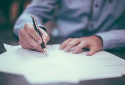 A person uses a pen to write on paper