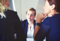 Three women in a business meeting, with one woman in focus listening intently