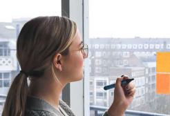 A person sticks Post It notes on a window