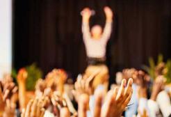 An audience waves at a person on stage