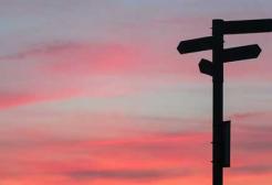 A signpost with a blue and pink sky behind it