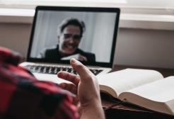 A person having a video call with someone shown on a laptop screen