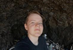 Wildlife Alumni, Cris, smiling into the camera with a rocky habitat in the background
