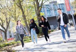 Four students walking outside through campus