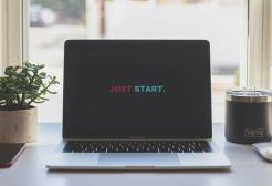 A desk showing a laptop, phone and mug