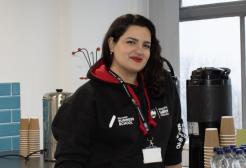 Woman stood at a kitchen bench smiling.