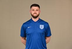 A man in a blue England football shirt posing for a photo.