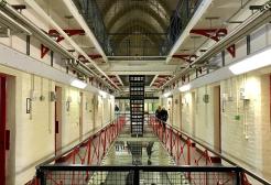 Photograph of the inside of a prison with people walking around. 