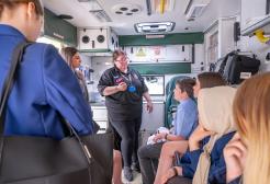 Young students sit in an ambulance talking to an NHS worker.