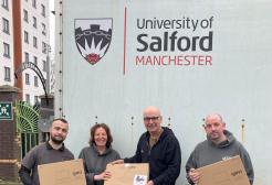 Four people holding laptop donation boxes