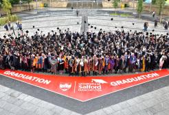 Graduates posing for a group photograph outside the The Lowry Building in Salford Quays