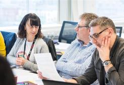 Three people sat around a table discussing notes