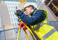 Construction apprentices using measuring instruments on outside