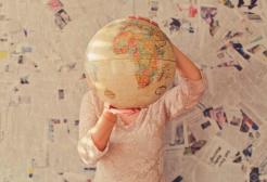 Person holding a globe against a wall of newspapers