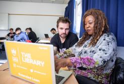 a male and female student working together on a laptop