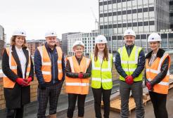 A group of six construction apprentices and employers on top of a building