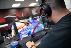 Student wearing headphones, using a workstation in the Esports Suite, Salford Business School
