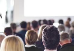 A group of people seated in a meeting room looking at a projection screen