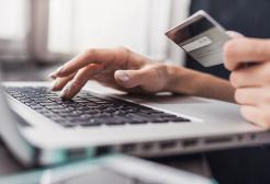 a person holding credit card in front of laptop