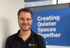 KTP associate Gabriel Whittle stands in front of a sign that reads creating quieter spaces together