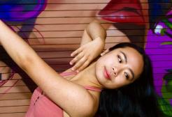A girl dancing in front of street art with her arm up and her head thrown back