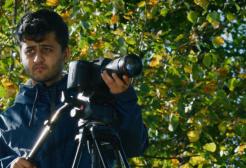 A man pointing a camera and searching for what to take an image on.