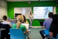 Image shows classroom with students hosting a presentation