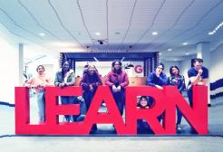 Eight students stood around the library learn sign
