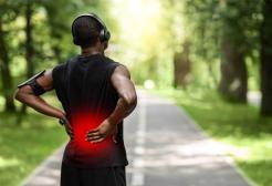Image shows a male runner holding his back