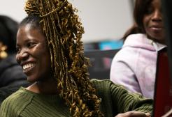 A female student smiling looking off camera in front of a desktop computer 