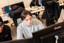 Three male students working together around three computer monitors