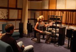 People sat in a room surrounded by audio equipment being setup