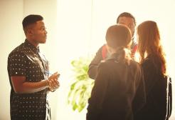 Four people stood together talking in front of a window