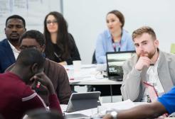 Six postgraduate students say in a lecture with laptops, tablets and note books