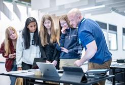 Four students and one supervisor looking at laptops