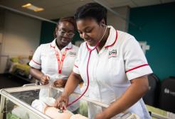 Two female student midwives conducting new-born checks.